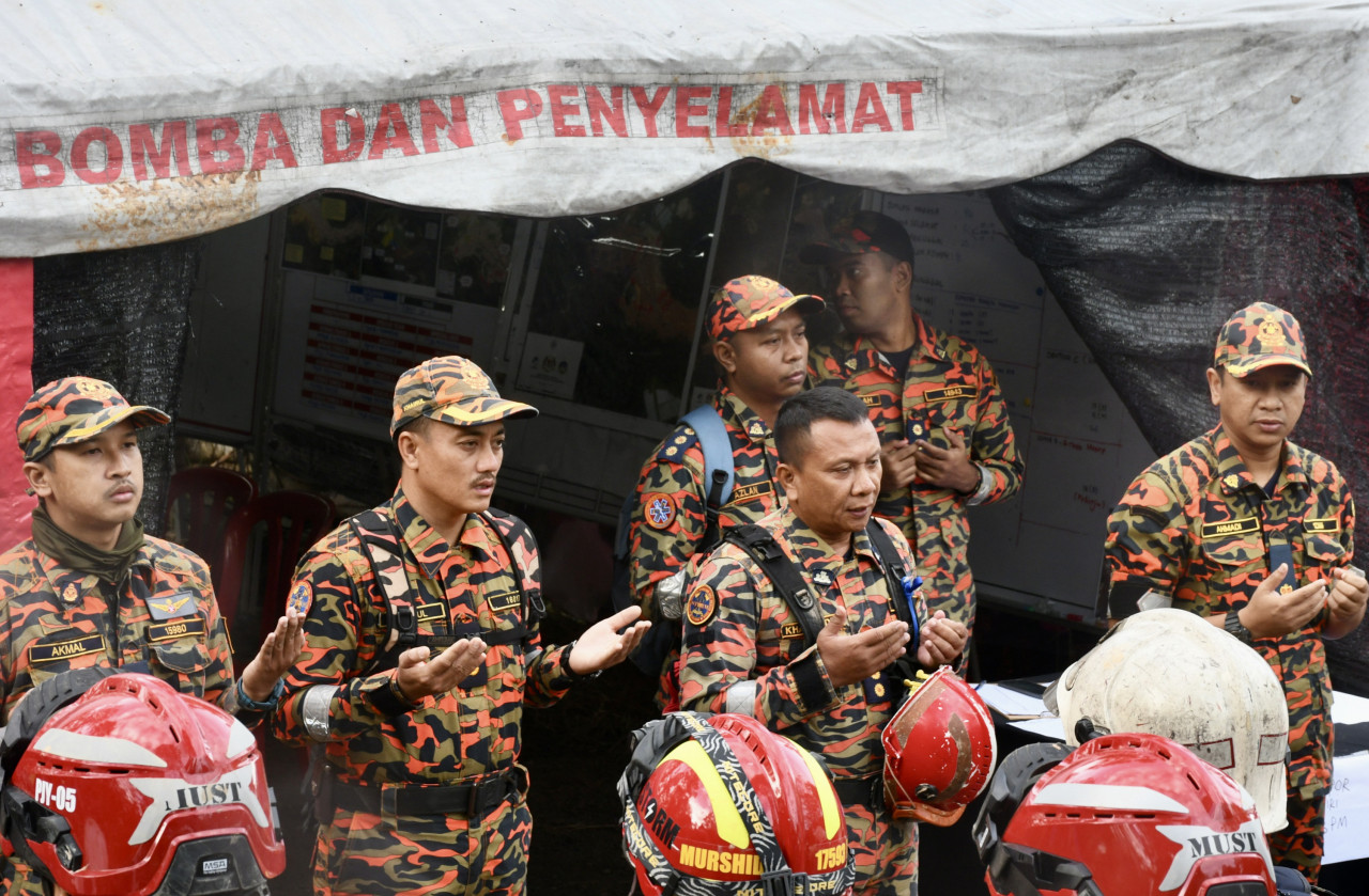 Fire and Rescue Department personnel recite prayers before commencing today’s search for landslide victims in Batang Kali. – Pic courtesy of Fire and Rescue Department, December 22, 2022