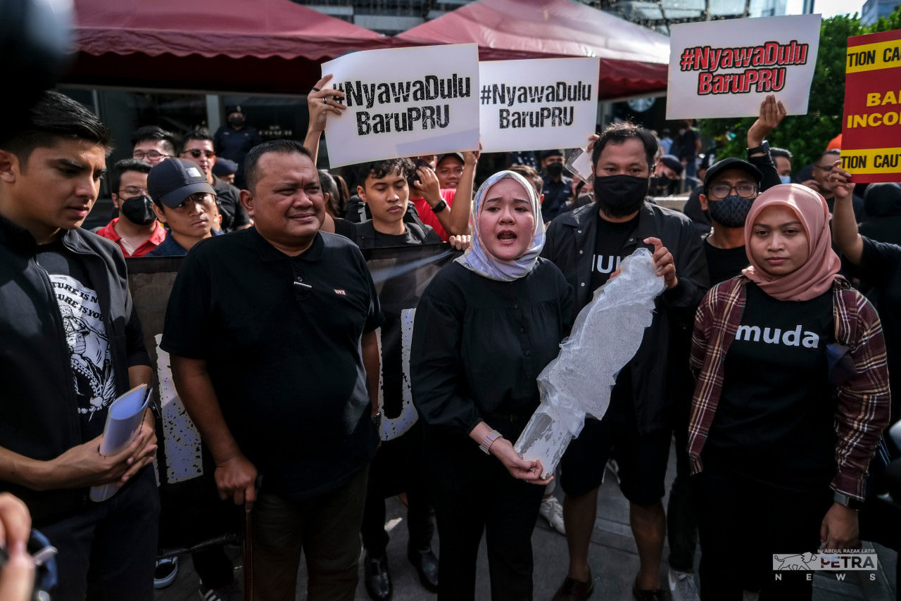 Muda central committee member Nurainie Haziqah Shafii (centre) holds a symbolic ‘batu nisan’ or the Muslim grave headstone to emphasise the risk floods bring to Malaysians, which might take lives. – ABDUL RAZAK LATIF/The Vibes pic, September 24, 2022
