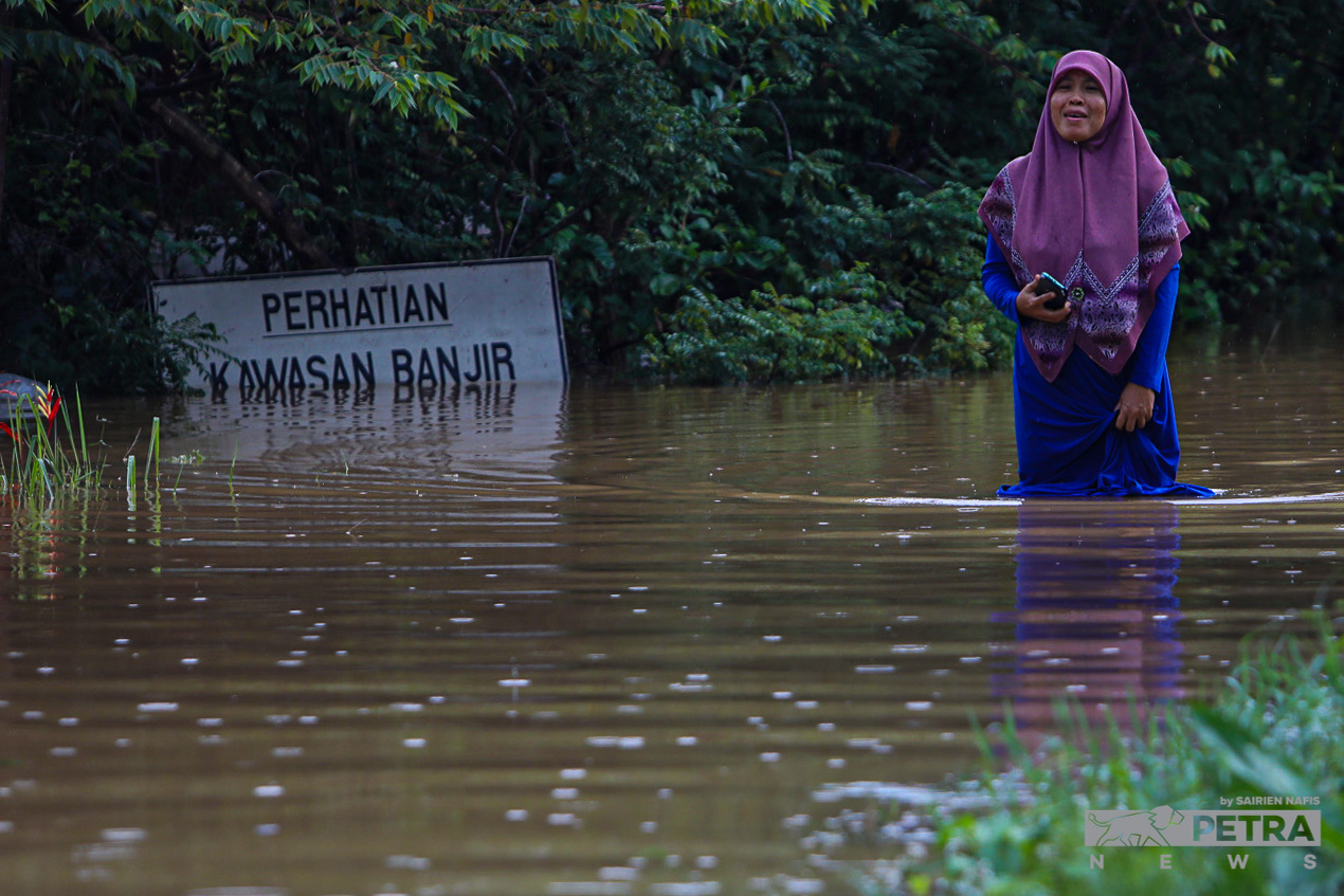 A woman wades through muddy flood waters in Meru. Year-end floods due to the monsoon season is an annual occurrence, but floods caused by heavier than usual rain due to climate change have also begun to occur more frequently at other times of the year. – SAIRIEN NAFIS/The Vibes pic, December 31, 2022