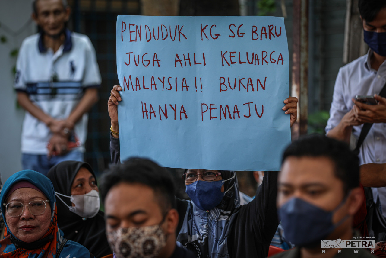 A resident holds up a placard saying ‘Kg Sg Baru residents are also members of the Malaysian Family, not just landowners’. – SYEDA IMRAN/The Vibes pic, August 29, 2022