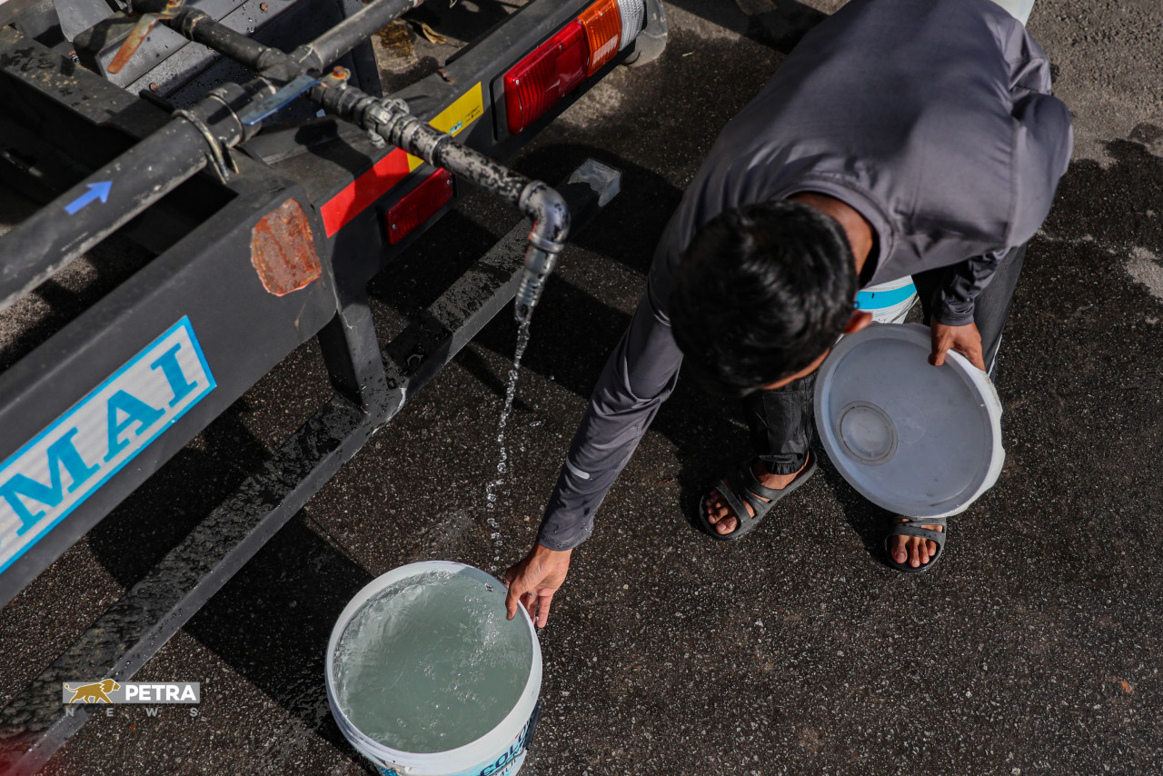 A Shah Alam resident filling an empty paint tub with water. – SAIRIEN NAFIS/The Vibes pic, March 31, 2021