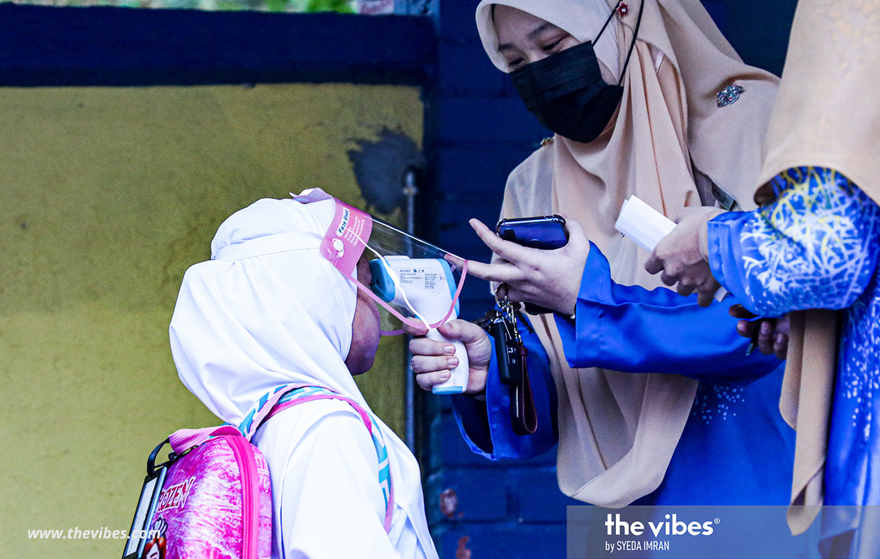 A young pupil getting her temperature taken before entering school today. – SYEDA IMRAN/The Vibes pic, March 1, 2021
