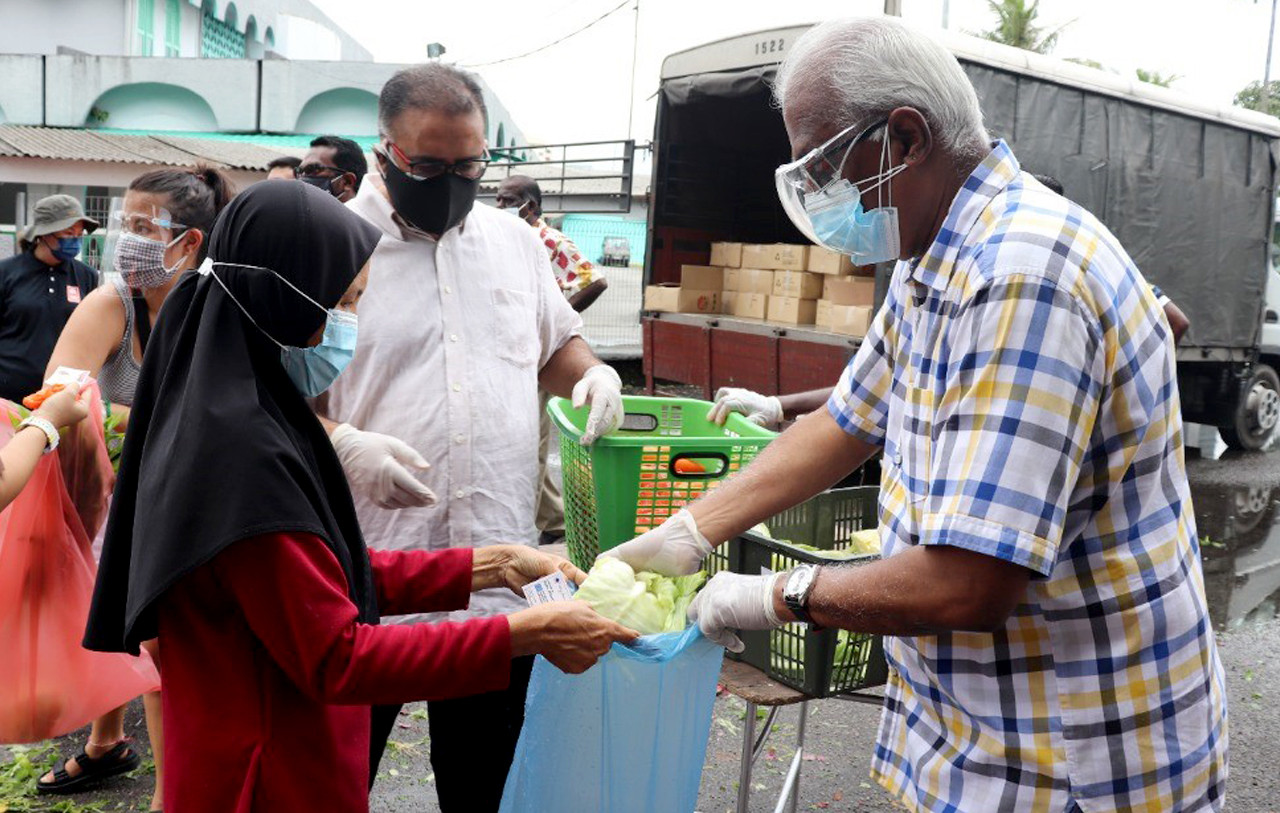 Klang MP Charles Santiago (right) handing over vegetables to a woman at the Ar-Rahman Mosque in Pandamaran Jaya, Klang. – Charles Santiago Office pic, July 15, 2021