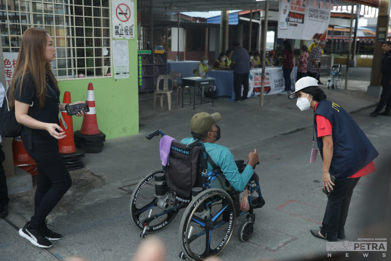 An Election Commission worker aids a disabled voter at the polling centre at SJK(C) Selayang Baru. – NOOREEZA HASHIM/The Vibes pic, August 12, 2023
