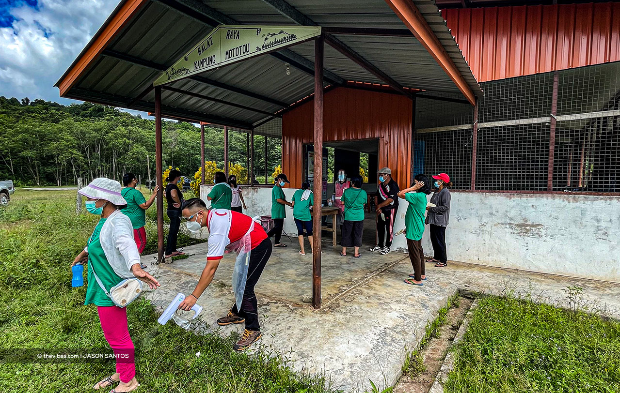 Villagers from Sook’s Kg Mototou gather at their community hall, where they are sprayed with sanitiser and have their names checked before getting food aid. – The Vibes pic, July 17, 2021