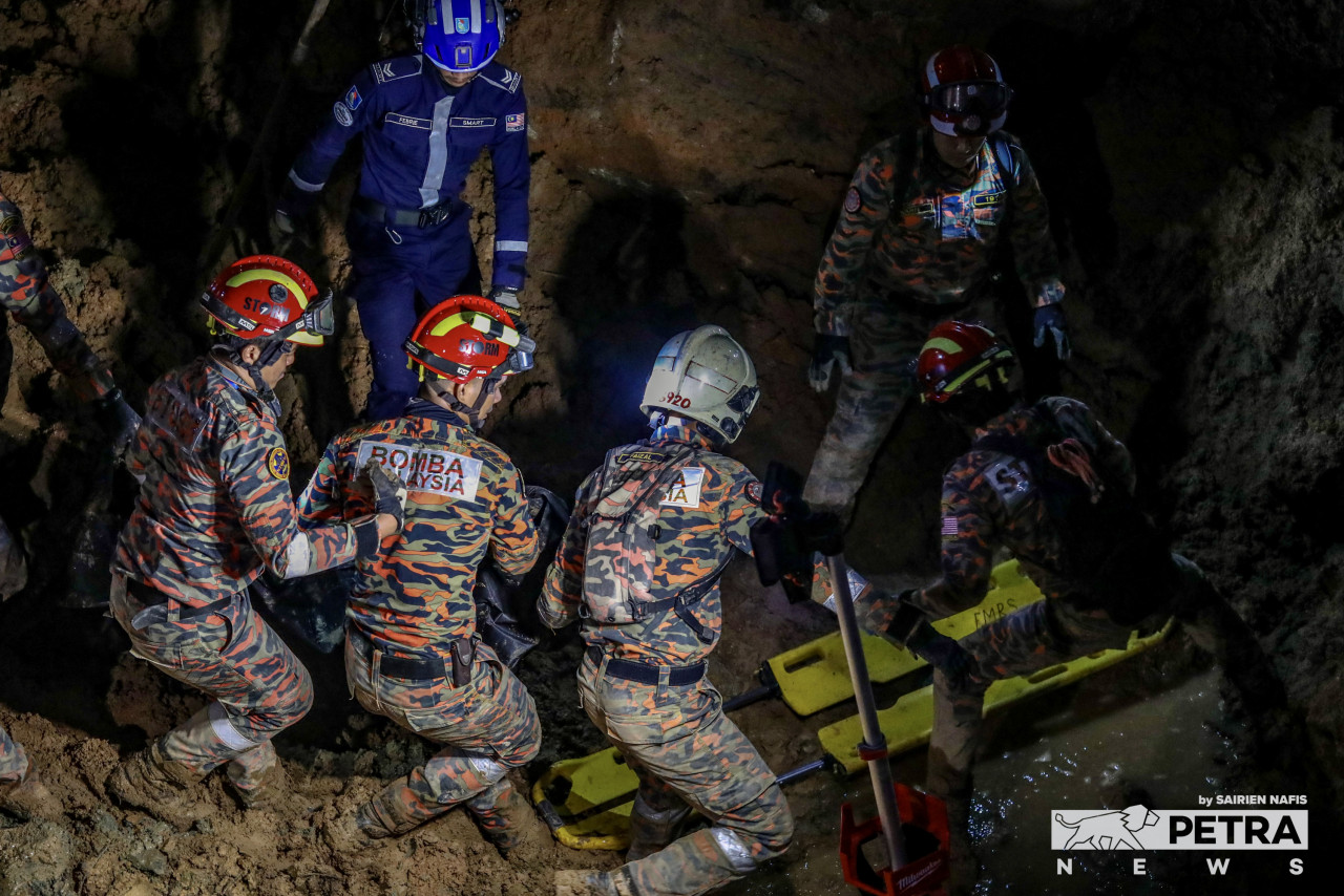 In muddy conditions and on unstable ground, Batang Kali landslide rescuers attempt to place the 25th victim’s body on a stretcher. – SAIRIEN NAFIS/The Vibes pic, December 21, 2022
